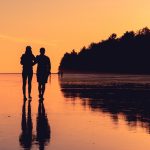 homem e mulher a caminhar numa praia